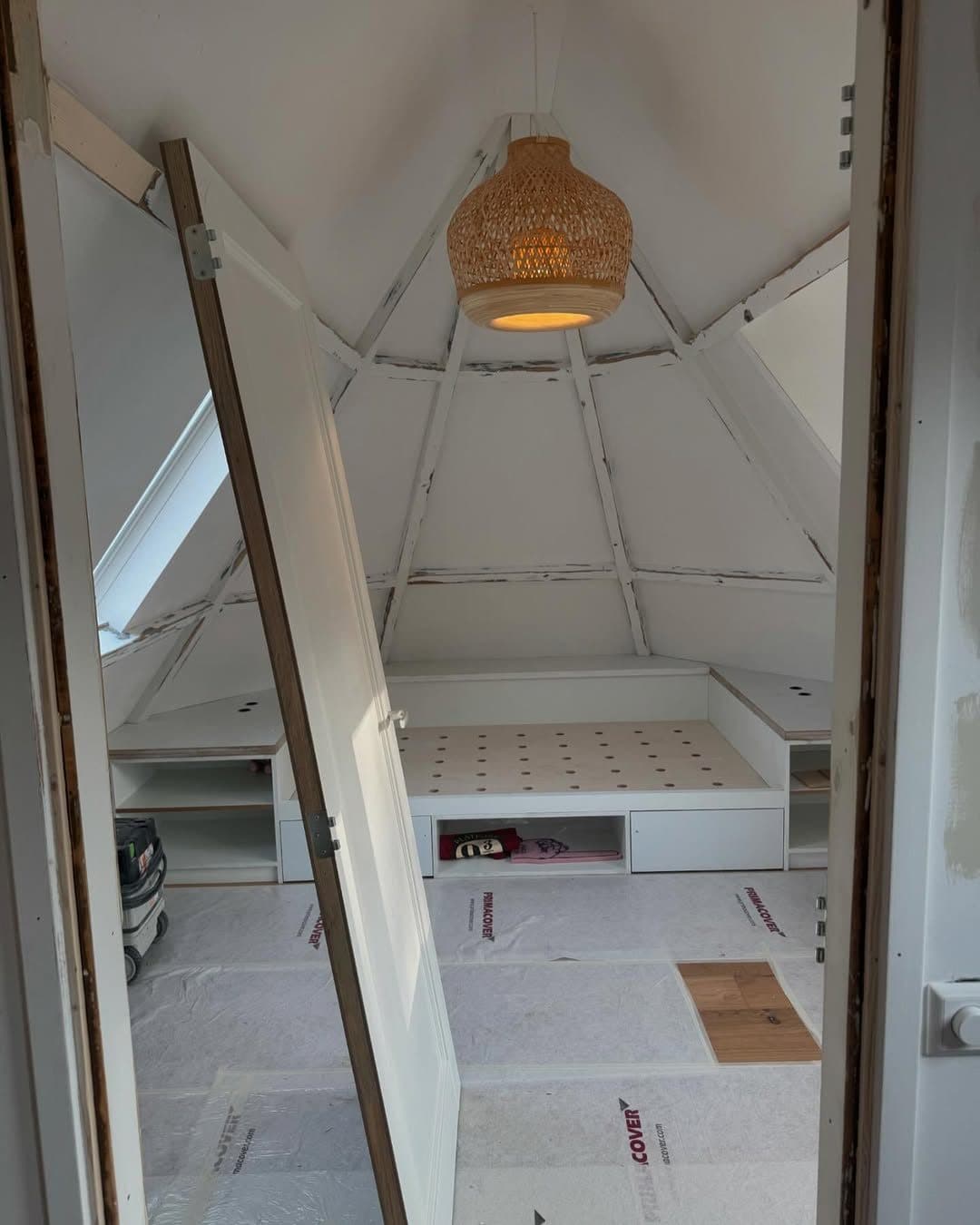 Zolderkamer tijdens het schilderwerk, balken nog kaal en vloer afgedekt