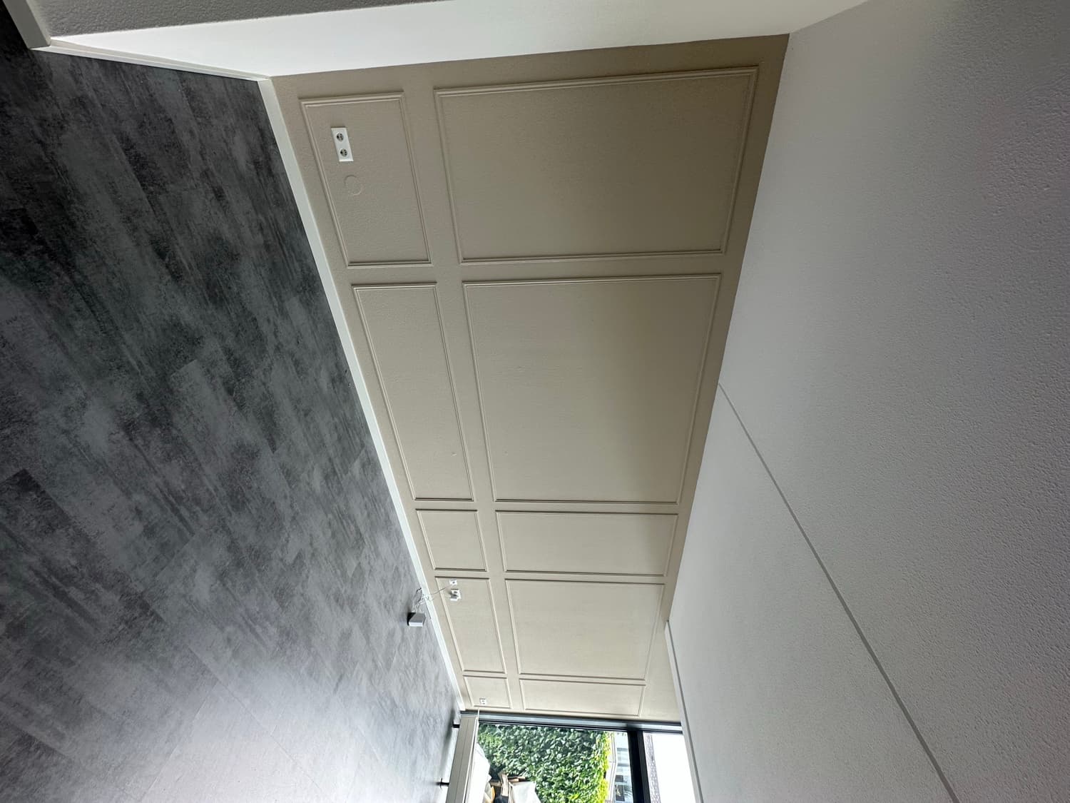 Afgewerkte wand vol sierlijst-panelen in taupe