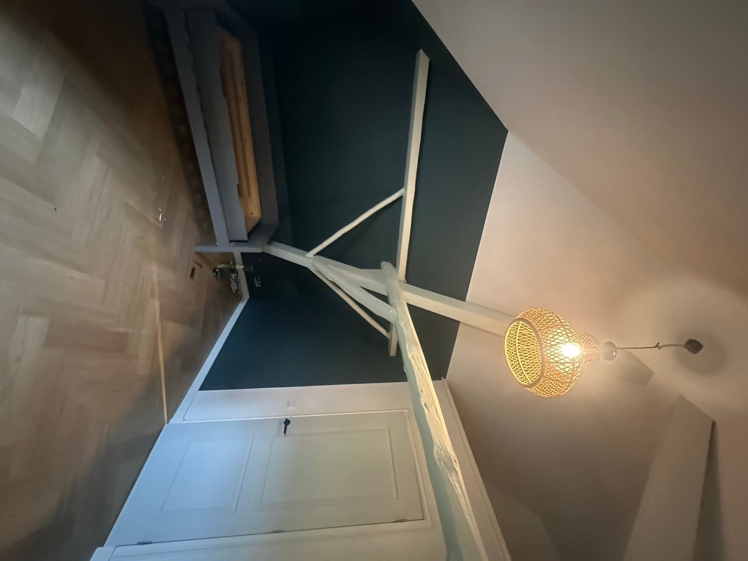 Dezelfde zolderkamer met diepgroene wand en wit gelakte balken