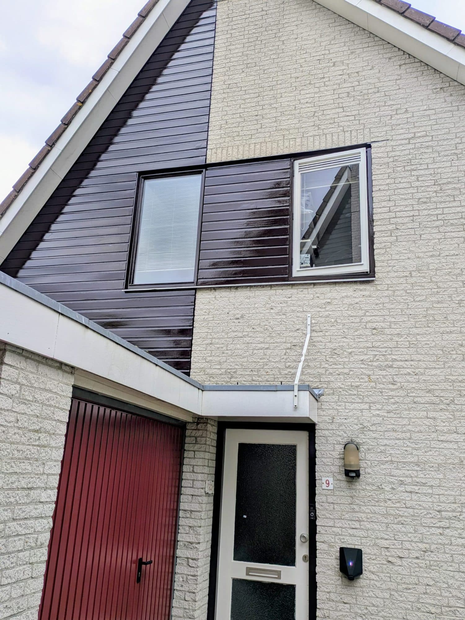 Donker gelakte houten rabatdelen op de bovengevel van een woning