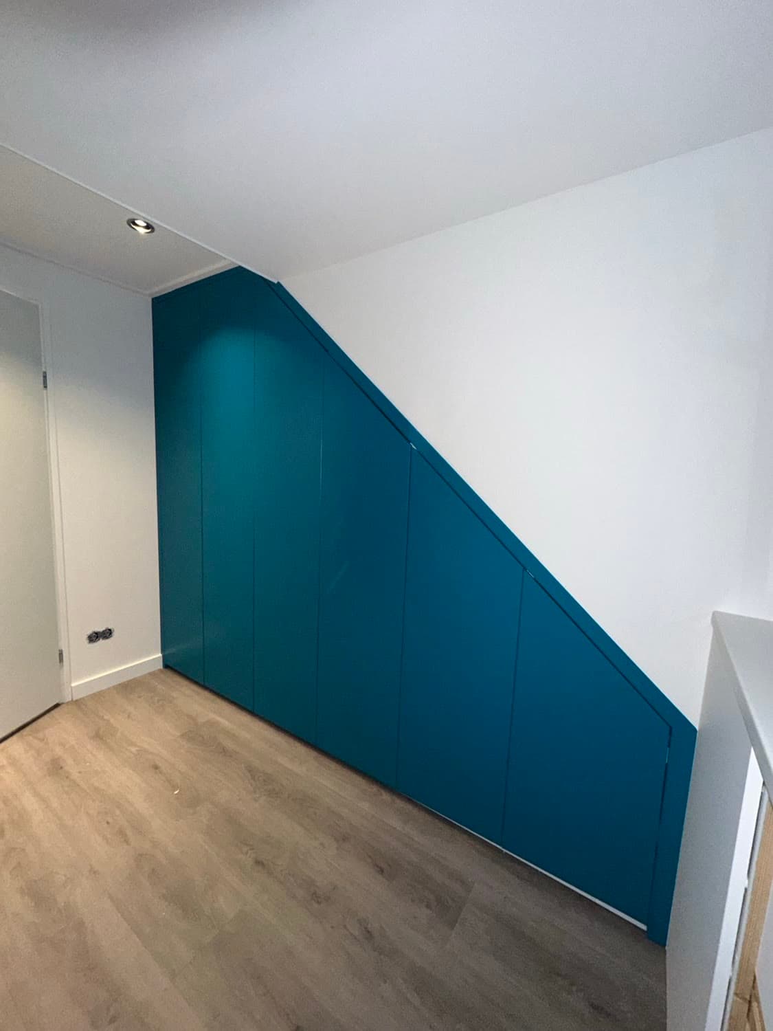 Made-to-measure cupboard in petrol, cleanly lacquered under a sloping roof