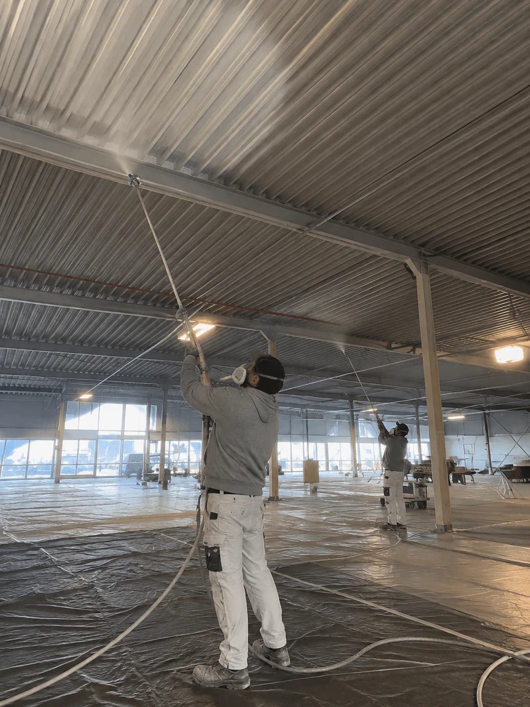 Two of our team spraying the ceiling of a commercial hall