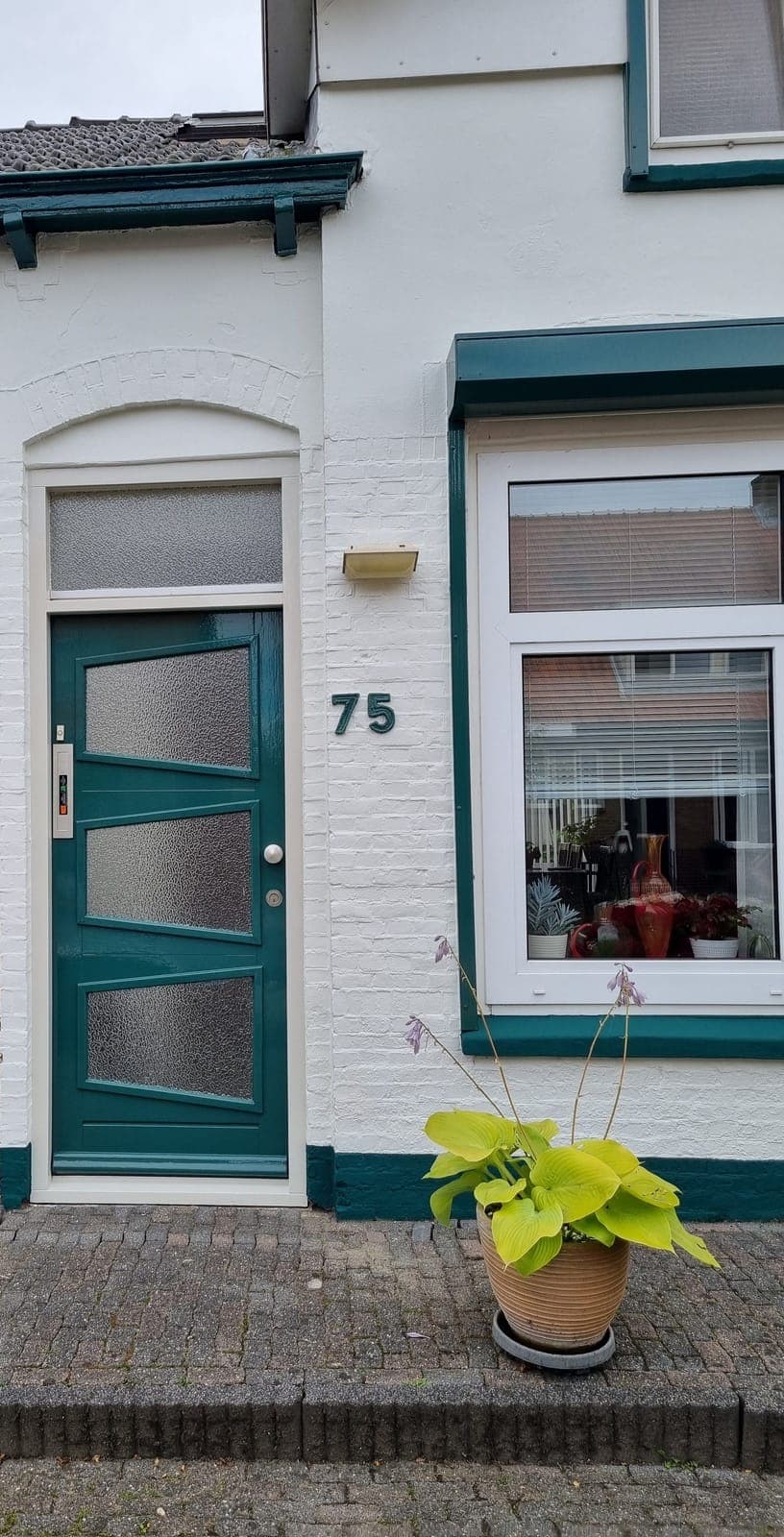 Groen gelakte voordeur in een wit geschilderde gevel